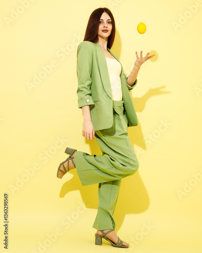 Obraz na płótnie Fashion portrait of beautiful model in green suit with lemons against yellow background w salonie