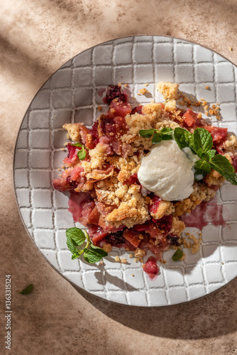 Apple crumble with ice cream on top decorated with mint leaves served in a plate on beige background in natural morning light. Sweet breakfast. Top view