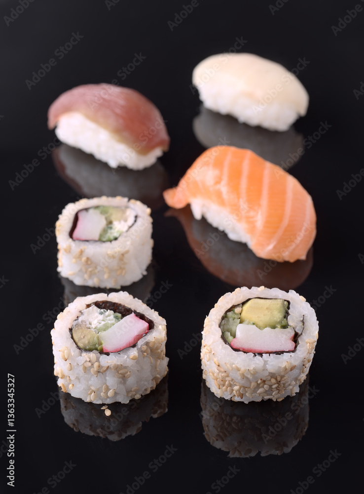 Sushi rolls and nigiri resting on reflective black surface Sushi rolls and nigiri resting on reflective black surface