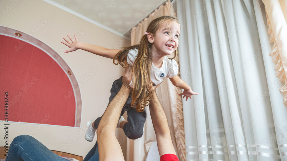Obraz premium Cheerful small girl daughter and her handsome young dad spending time together at home.