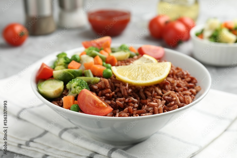 Delicious brown rice with vegetables and lemon slices served on grey table, closeup Delicious brown rice with vegetables and lemon slices served on grey table, closeup