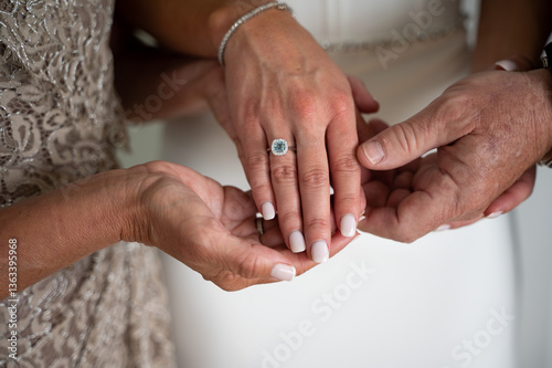 Close-up of bride’s engagement ring held by loving parents
