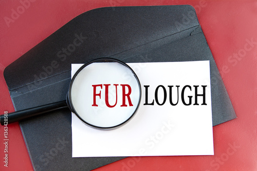 FURLOUGH - word on white paper lying on a black envelope on a red background