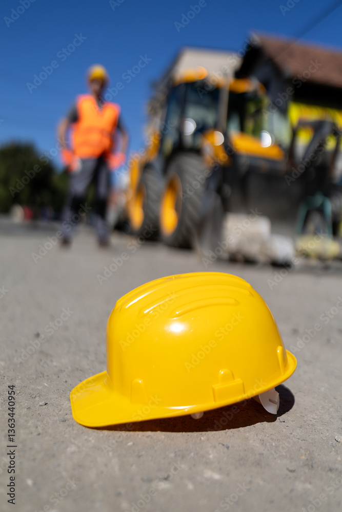 Construction workers on site with equipment and a yellow safety helmet placed on the ground Construction workers on site with equipment and a yellow safety helmet placed on the ground