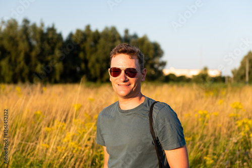 42 yo man with sunglasses, standing in the evening sun with a golden corn field in the background, Ghent, East Flanders, Belgium