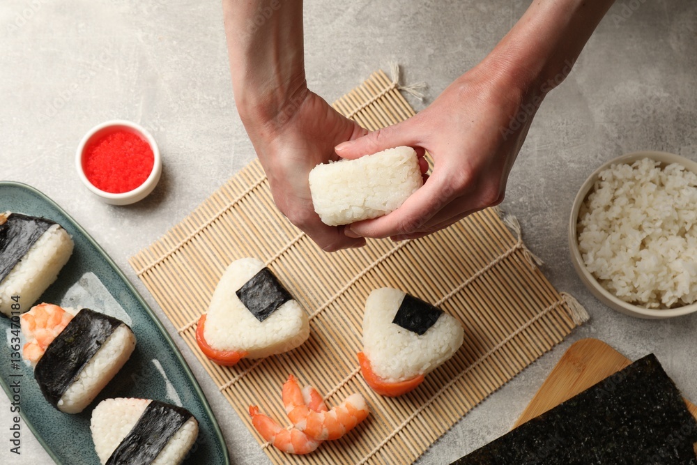 Fototapeta premium Woman making onigiri (Japanese rice balls) at light table, top view