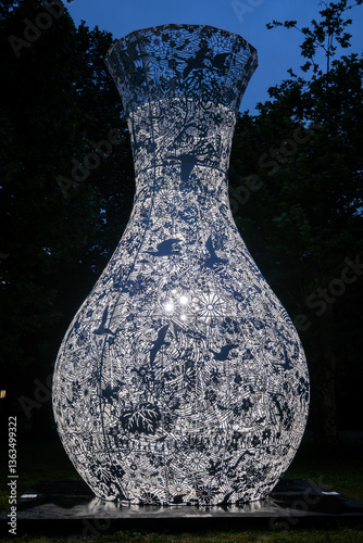 Intricate cutpaper style vase sculpture. The delicate, backlit botanical motifs and bird silhouettes create a stunning juxtaposition of nature and art. Ethereal illumination. photo