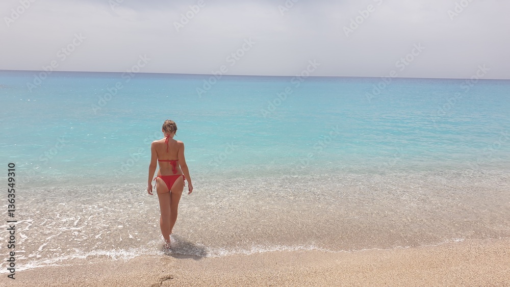 A Woman in a Red Bikini Walking into the Turquoise Waters of the Ocean A Woman in a Red Bikini Walking into the Turquoise Waters of the Ocean