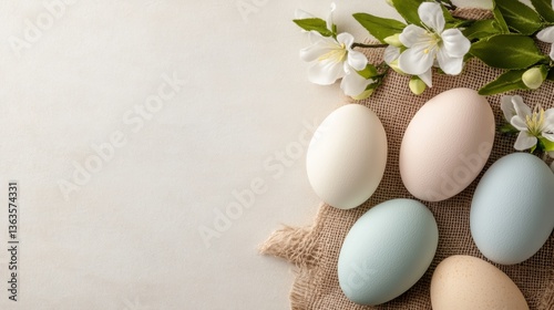 Pastel colored eggs arranged with delicate flowers on a rustic burlap background during springtime decoration preparation