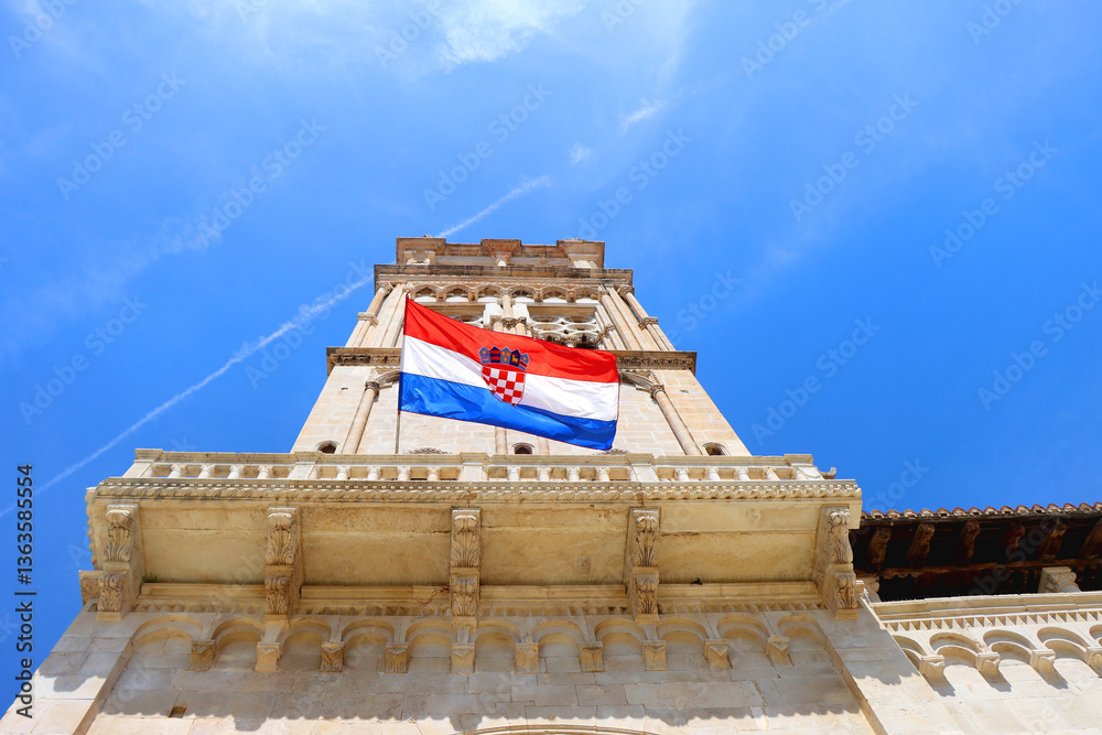 Croatian flag blowing in the wind on the bell tower of The Cathedral of St. Lawrence, landmark in Trogir, Croatia.