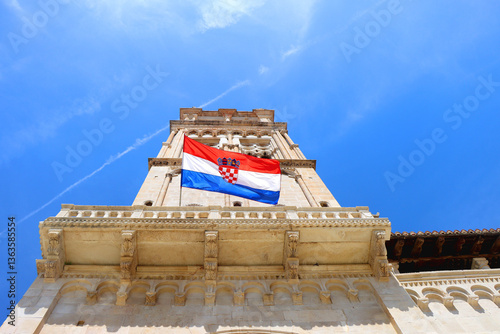 Croatian flag blowing in the wind on the bell tower of The Cathedral of St. Lawrence, landmark in Trogir, Croatia.