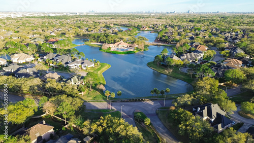 Lakeside upscale gated community in unincorporated area northwestern Harris County, Houston with downtown skyline distance background, row of expensive mansion homes with swimming pools, aerial