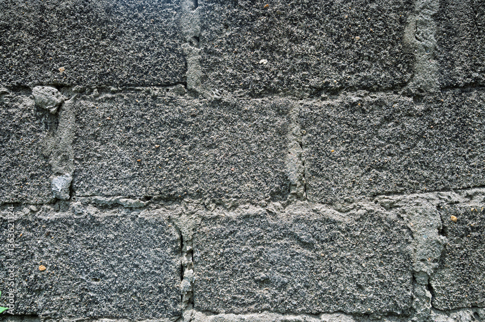 A rough-textured concrete brick wall with visible mortar lines, captured in black and white, emphasizing texture and contrast in an urban setting. A rough-textured concrete brick wall with visible mortar lines, captured in black and white, emphasizing texture and contrast in an urban setting.