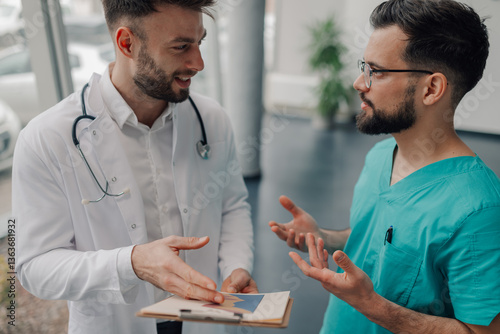 Doctor and nurse discussing medical chart in hospital corridor