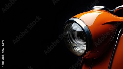 Orange vintage scooter headlight, dark background, classic design, transportation