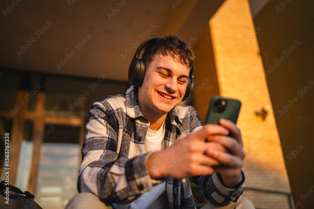Fototapeta premium young man student sit in front university listen music and enjoy