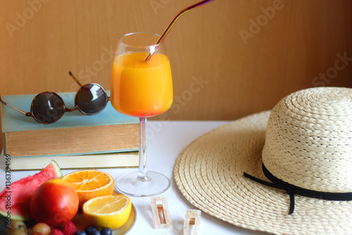 Obraz na płótnie Glass of cocktail, straw hat, sunglasses, books, fresh fruit, chocolate and accessories. Summer essentials on the table. Selective focus. w salonie