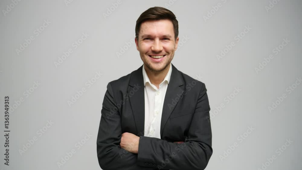 Smartly dressed man poses confidently with a friendly smile against a grey backdrop. Smartly dressed man poses confidently with a friendly smile against a grey backdrop.