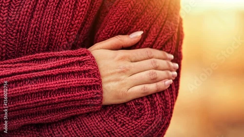Warm embrace of a person wearing a cozy red sweater in a golden sunset atmosphere