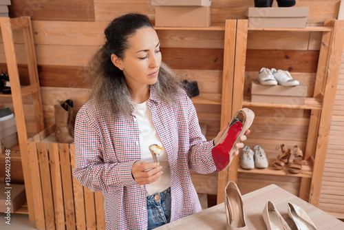 Female shoemaker repairing high-heeled shoe in workshop