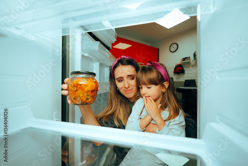 Mother and Daughter Find One Last Jar of Food in the Fridge . Mom forgetting to re stock the refrigerator not having enough food 