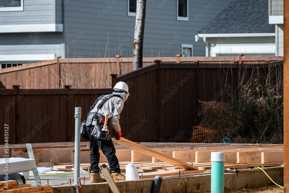 Construction worker, carpenter, in tool belt and hard hat on housing development project, installing subfloor wood on cement foundation, stacks of lumber, sunny winter day
Construction worker, carpenter, in tool belt and hard hat on housing development project, installing subfloor wood on cement foundation, stacks of lumber, sunny winter day
