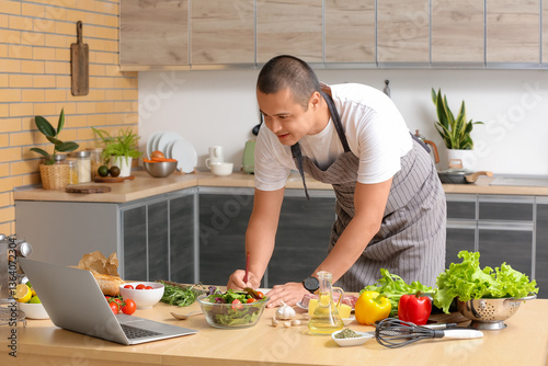 Young man with laptop makin...