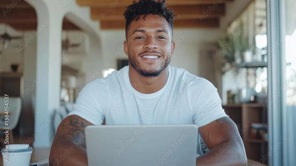 Obraz premium Confident young man smiling at laptop in bright workspace, showcasing positive attitude