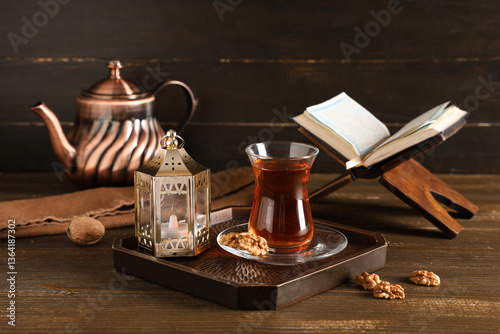 Photography Tray with glass of tasty Turkish tea, fanoos, and Koran on wooden table