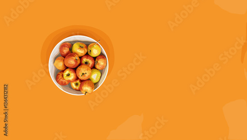 Fresh apples in a bowl against a vibrant orange background  