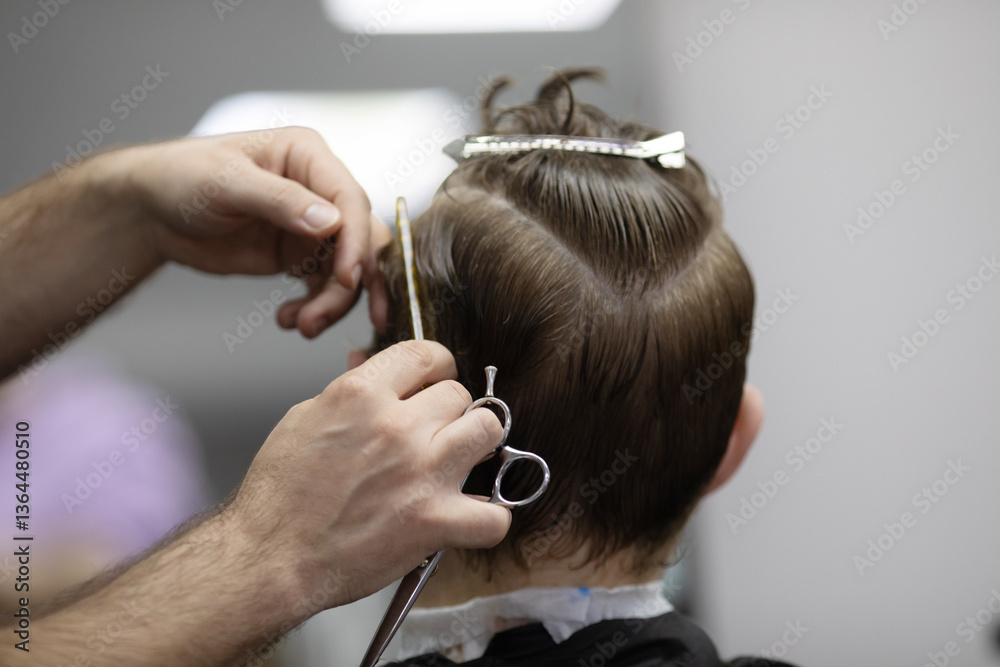 Fototapeta premium man is cutting a child's hair. The man is holding a pair of scissors and the child is sitting in a chair
