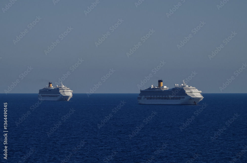 Obraz premium Mega family cruiseship cruise ship liners Favolosa and Fortuna anchored offshore of Civitavecchia Rome, Italy before reactived after Covid pandemic with other vessels in port and coastline