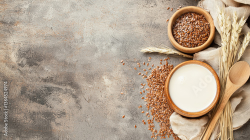 Fresh flaxseed milk in bowl surrounded by flaxseeds, oats, and wooden spoon on textured background, evoking natural and wholesome feel