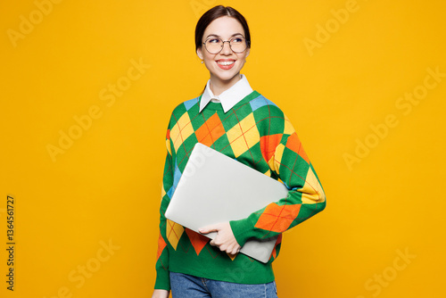 Obraz na plátně Side view young IT woman wear glasses green sweater casual clothes hold use closed laptop pc computer look aside on area isolated on plain orange yellow background studio portrait