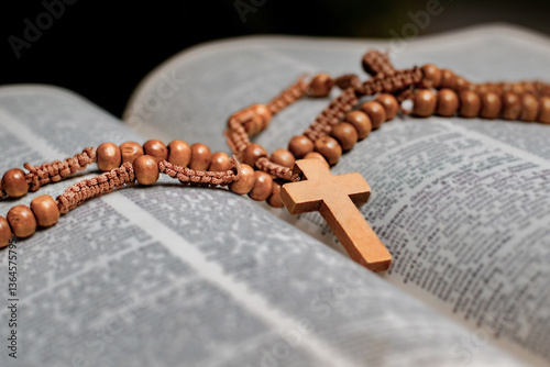 Fényképezés Christian wooden crucifix necklace placed on opened page book, soft focus, concept for bible study of christanity priests