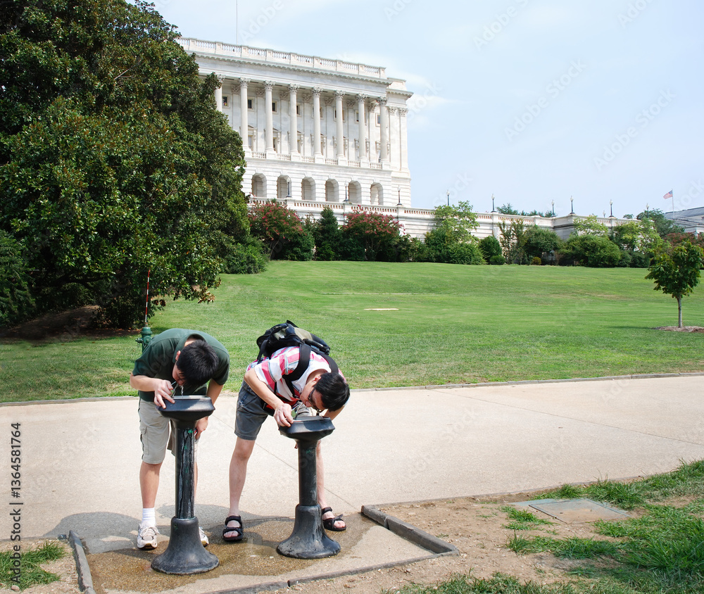 Tourists drink water from a water fountain outside Capitol Hill on a hot summer day. Washington D.C.