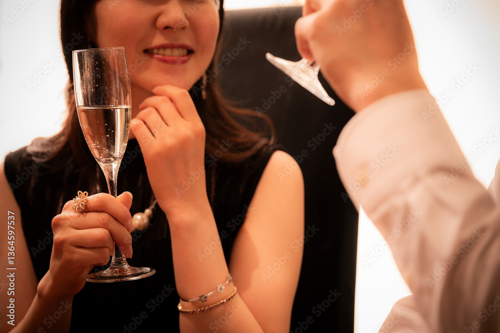 Detailed close-up shot of two champagne flutes clinking together during a toast at an elegant bar. The hands, jewellery, and bubbles emphasize sophistication and celebration.