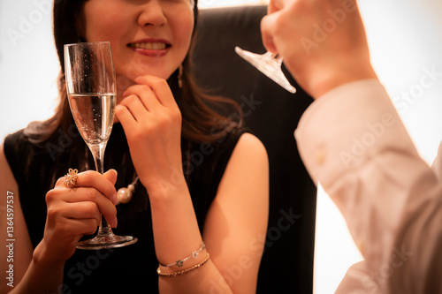 Obraz na płótnie Detailed close-up shot of two champagne flutes clinking together during a toast at an elegant bar. The hands, jewellery, and bubbles emphasize sophistication and celebration. w salonie