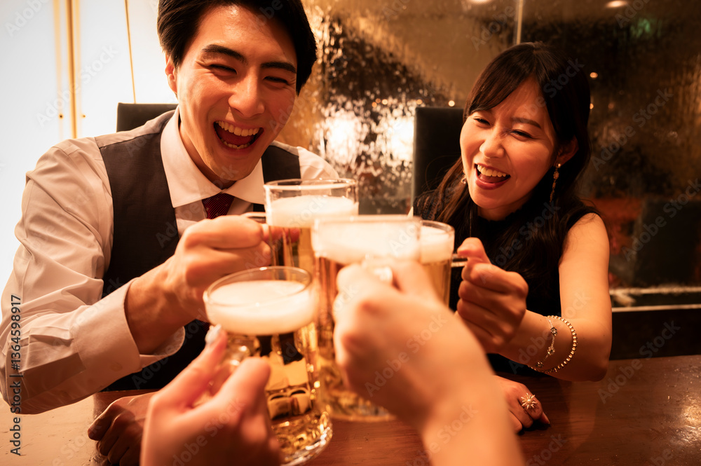A man and woman enthusiastically toast their beer mugs with a group of friends at a bar. Everyone is laughing, and the atmosphere is filled with energy, fun, and connection.
