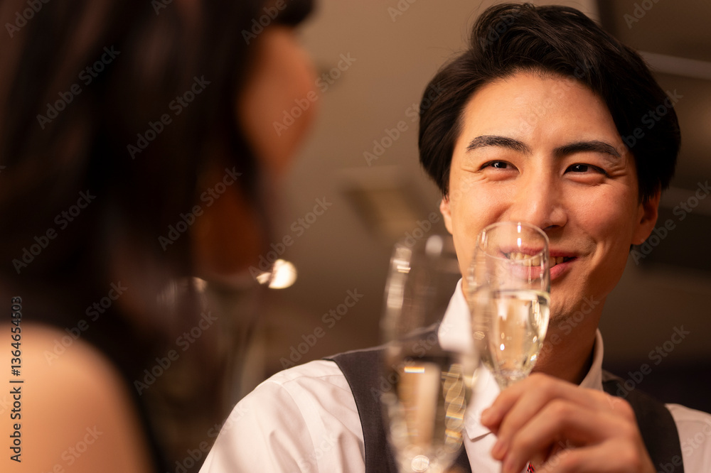 Close-up of a smiling man in a white shirt and vest holding a champagne glass, sharing an intimate moment during a romantic evening date at a stylish bar. Close-up of a smiling man in a white shirt and vest holding a champagne glass, sharing an intimate moment during a romantic evening date at a stylish bar.