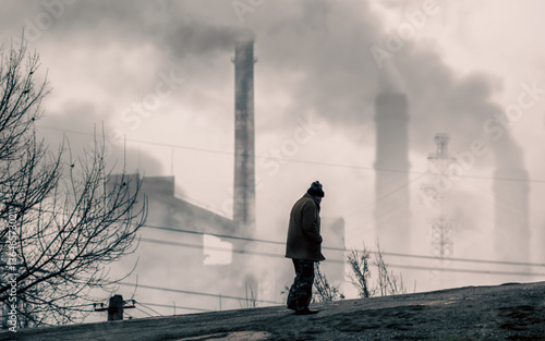 lonely beggar man on the background of smoking chimneys of a factory in Ukraine