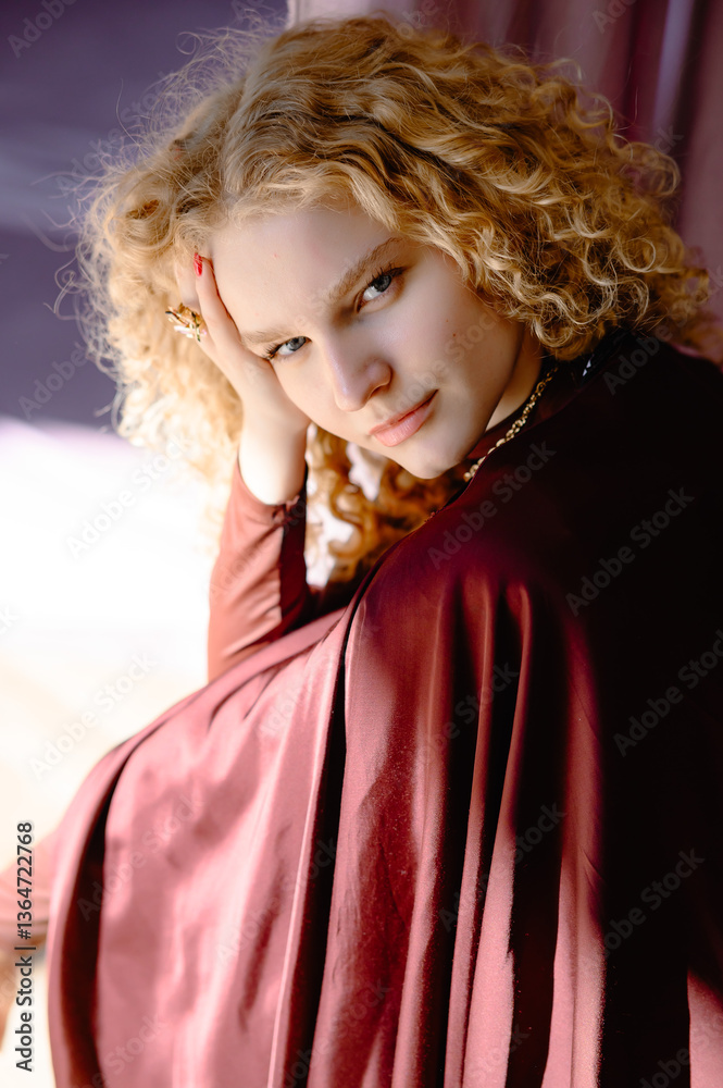 Fototapeta premium Portrait of a woman with white curly hair, in burgundy clothes creating an atmosphere of harmony. Exquisite accessories and burgundy outfit emphasize the elegance and style of the model.