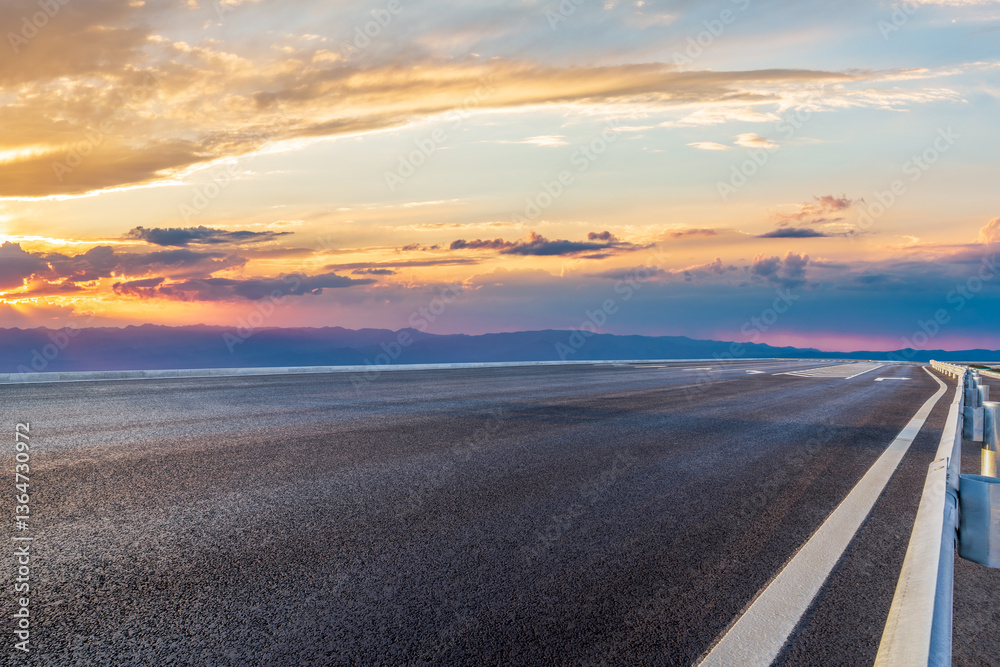 Fototapeta premium Asphalt road under sunset sky with colorful clouds
