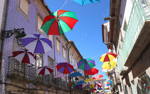 Colorful umbrellas over alley in typical architectural style using fixtures of buildings with azulejos, Viana do Castelo, Portugal