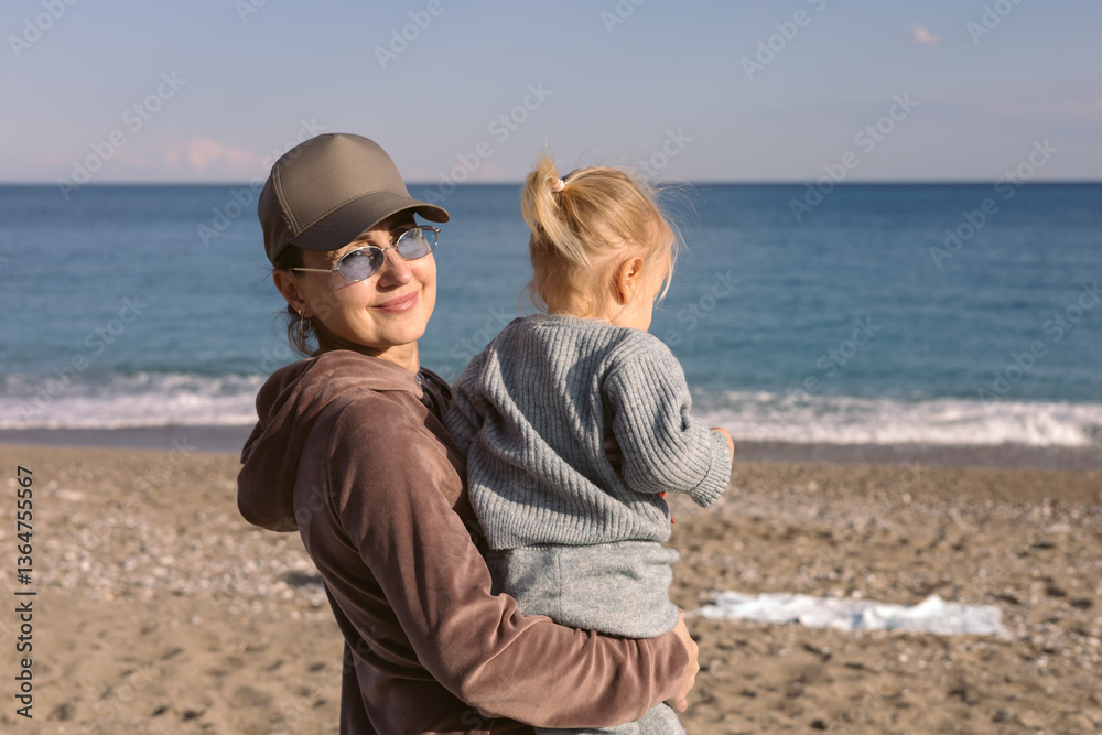 Mother and daughter enjoying a sunny day at the beach near the ocean shoreline Mother and daughter enjoying a sunny day at the beach near the ocean shoreline
