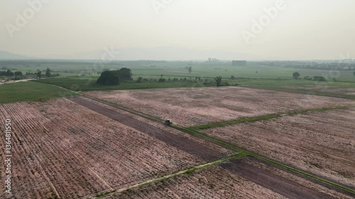 Aerial Landscape of Tranquil Agriculture Plowed Fields, Dirt Road, and Distant Mountains Under Hazy Horizon in Rural Natures Embrace