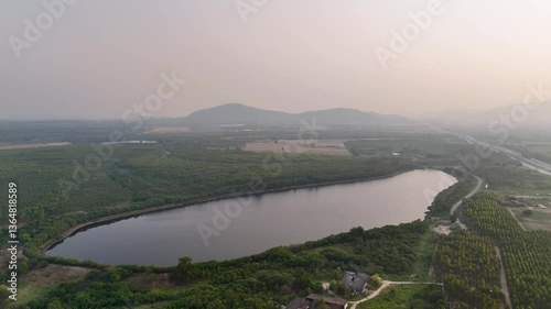 Aerial Landscape of Tranquil Lake at Dusk, Surrounded by Lush Greenery and Rolling Hills, Reflecting Natures Beauty and Serenity in Water.