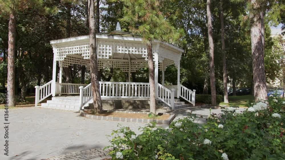 Beautiful park gazebo surrounded by blooming rose bushes on a sunny day in the heart of the city