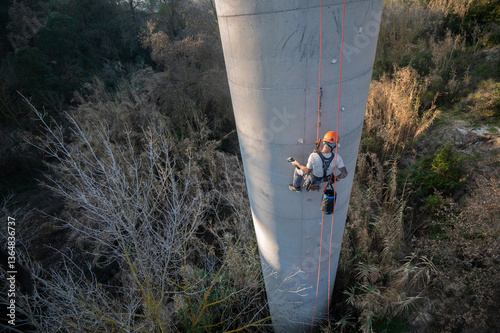 Rope access technician installing anchorages on concrete chimney