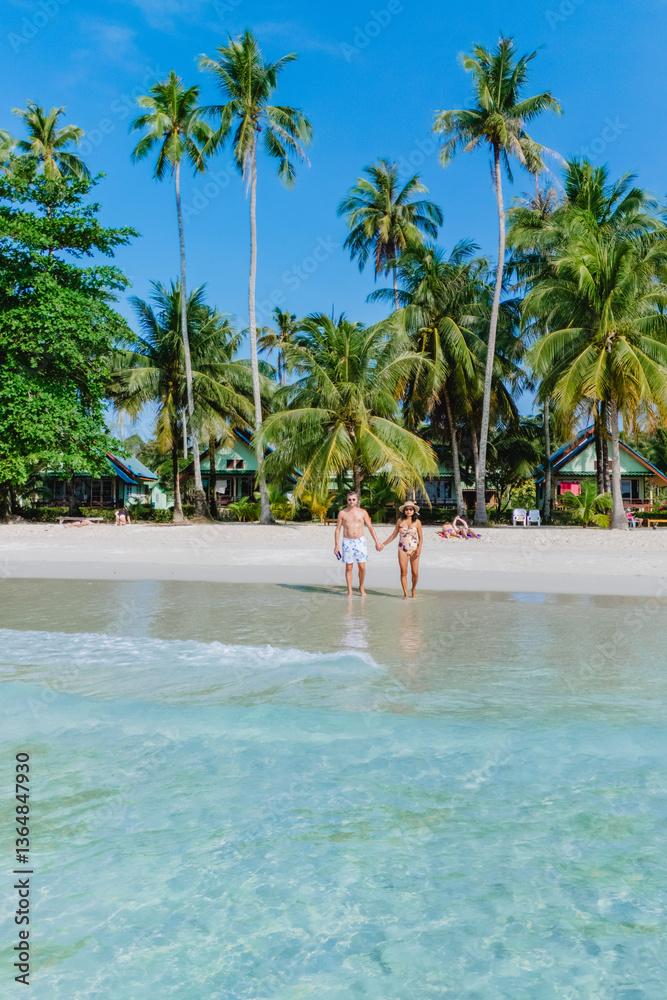 Obraz premium On a sunny day at Koh Kood Island beach, a women and men relax among palm trees and turquoise waters, seeking tranquility and joy in their tropical paradise, enjoying natures beauty of Thailand